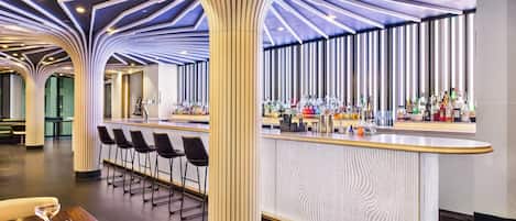 A modern bar area with a curved counter, bar stools, and a unique ceiling design.