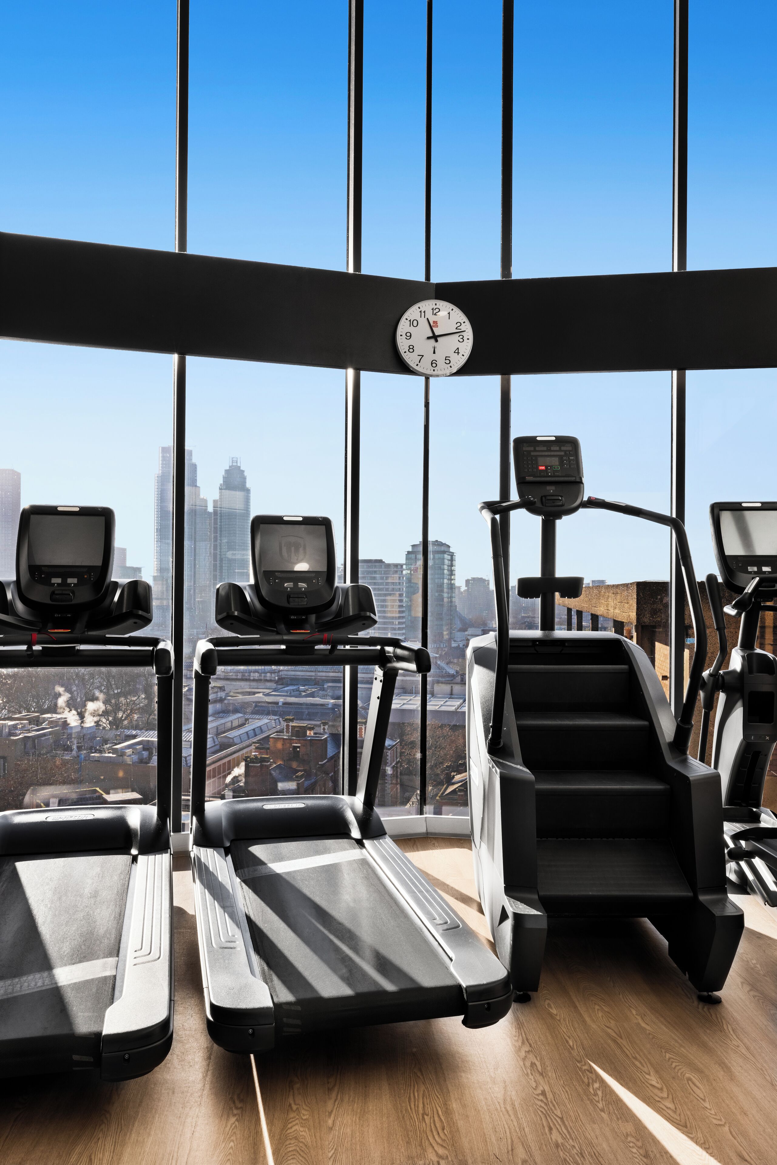 Un gimnasio con cintas de correr, una escaladora y un reloj digital.