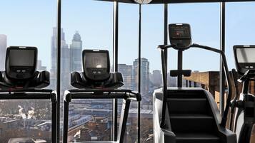 Un gimnasio con cintas de correr, una escaladora y un reloj digital.