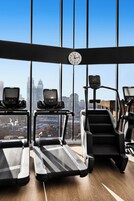 Ein Fitnessraum mit Laufbändern, Stepper und einer digitalen Uhr.