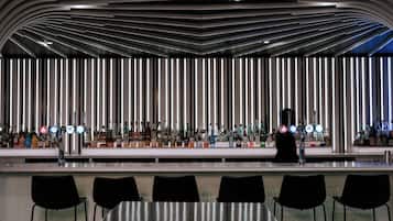 Un bar moderno con un techo elegante y curvo, y una hilera de paneles de luz verticales.