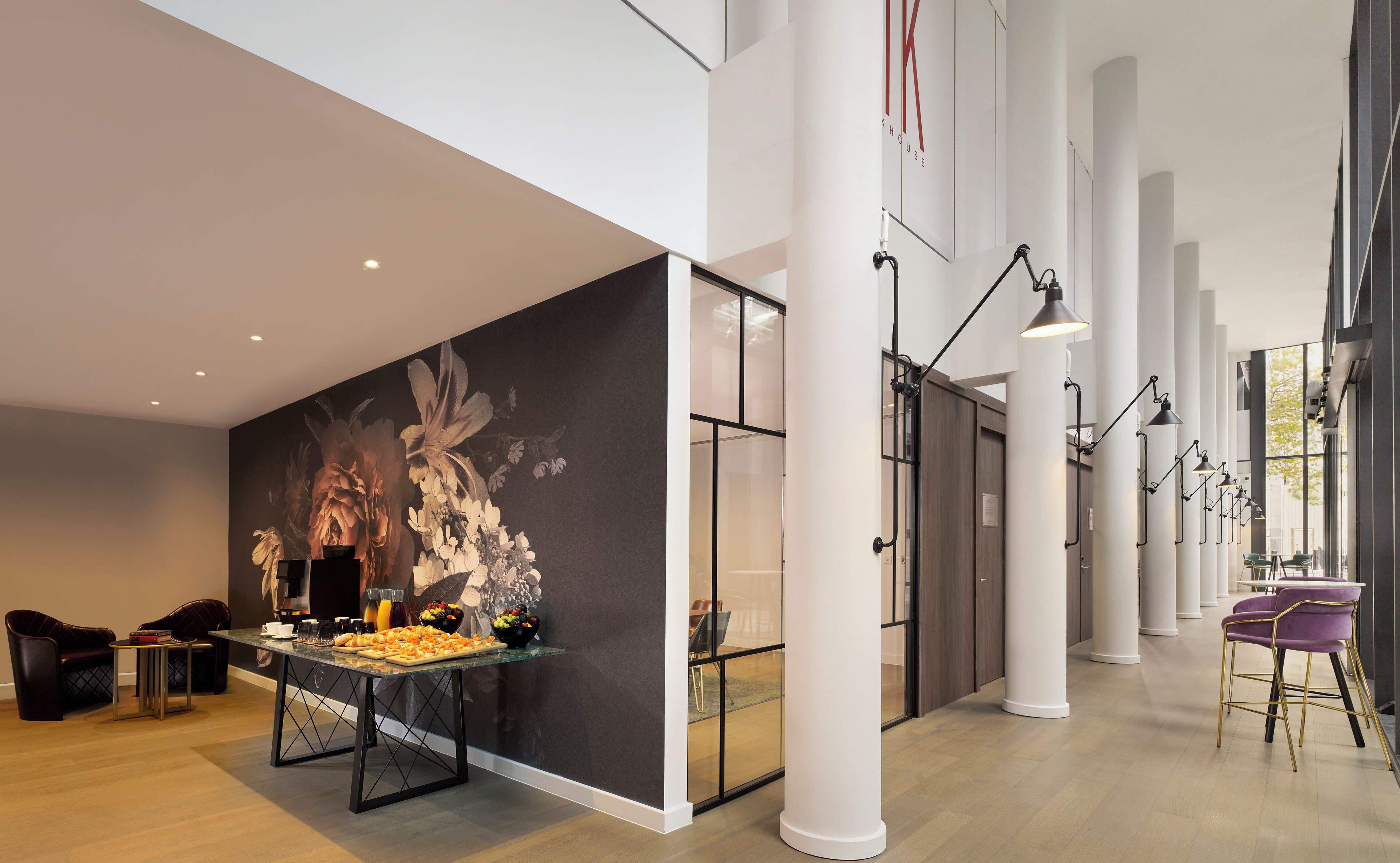 A modern interior with a glass partition, a dining area with a table set for a meal, and a seating area with chairs.