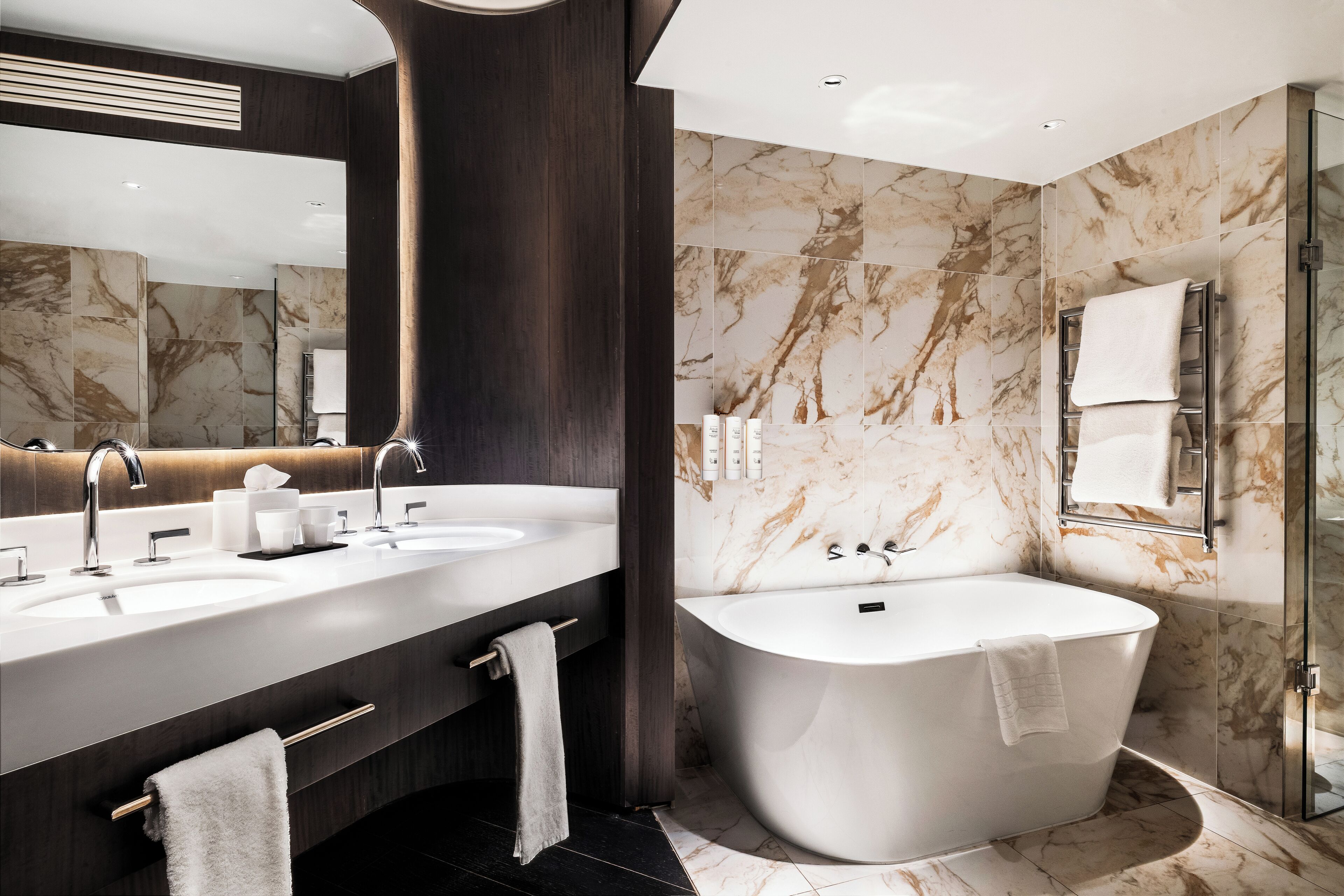 A modern bathroom with two sinks, a bathtub, and a glass shower enclosure.