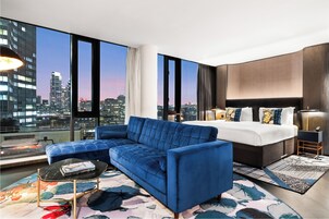 Ein modernes Hotelzimmer mit einem großen Bett, einem blauen Sofa und Blick auf die Stadt.
