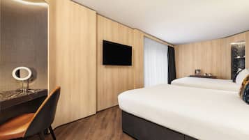 A hotel room with a bed, a desk with a chair, a television, and a mirror.