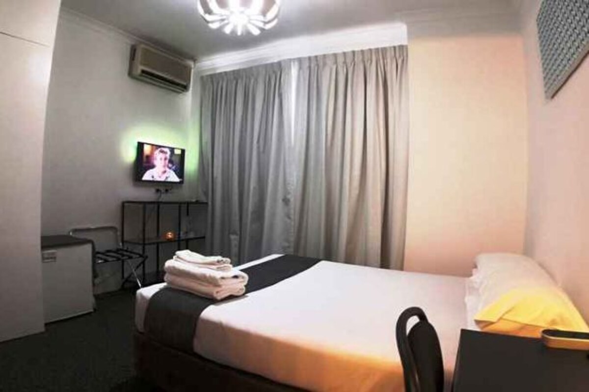 A hotel room with a bed, a television, a desk, and a chair.