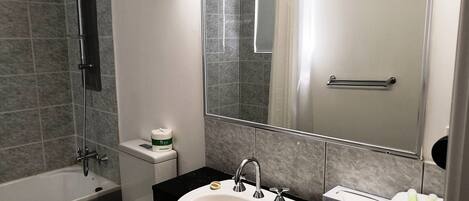 A bathroom with a bathtub, toilet, sink, and a large mirror.