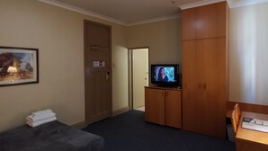 A hotel room with a bed, a TV on a wooden cabinet, a door, and a framed picture on the wall. - Criterion Hotel Perth (Perth)