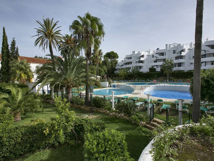 Ein Resort mit mehreren Pools, Palmen und einem weißen Gebäude mit Balkonen.