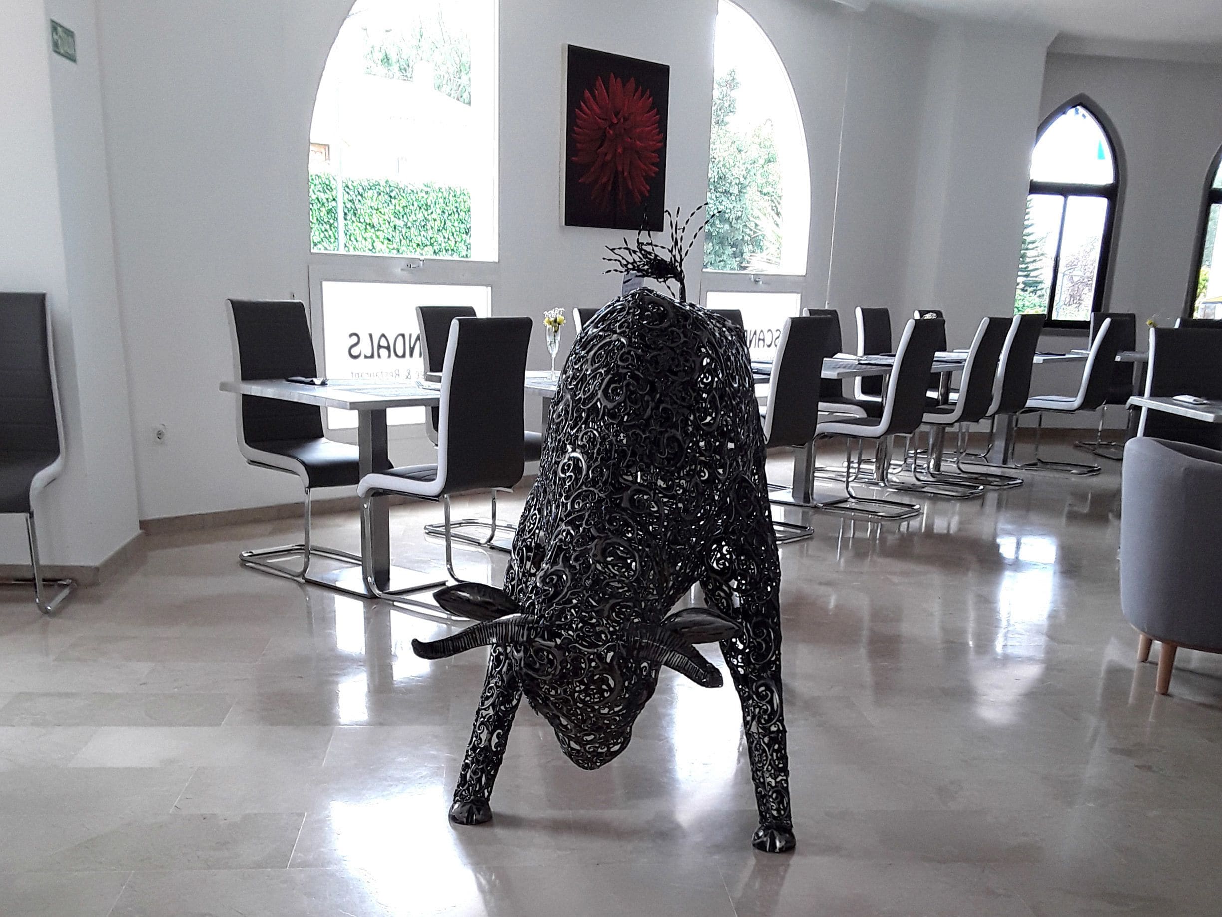 A modern interior with a unique black metal sculpture, white walls, and large arched windows.