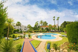 A resort with multiple swimming pools, palm trees, and lounge chairs. - Apartamentos Ona Campanario (Mijas)