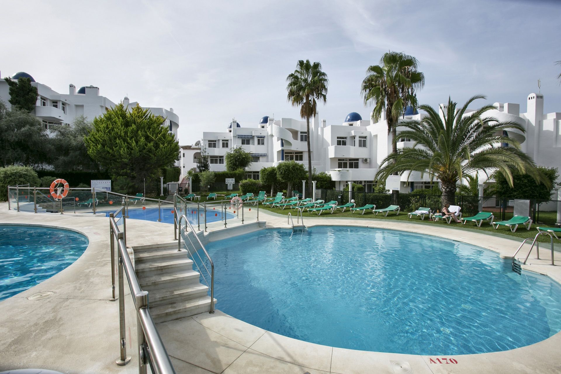 Une piscine à l’eau d’un bleu cristallin, entourée de chaises longues et de palmiers.