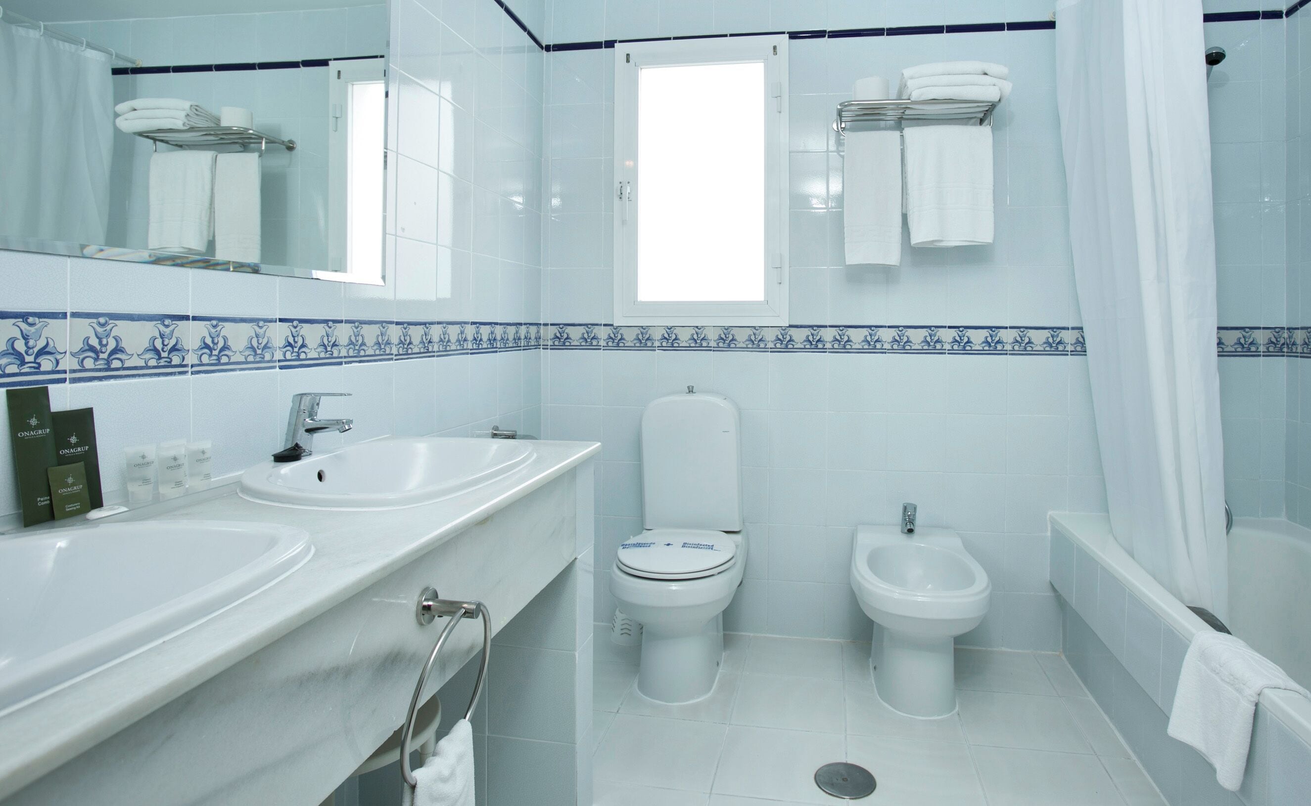 A bathroom with two sinks, a toilet, a bidet, and a shower.