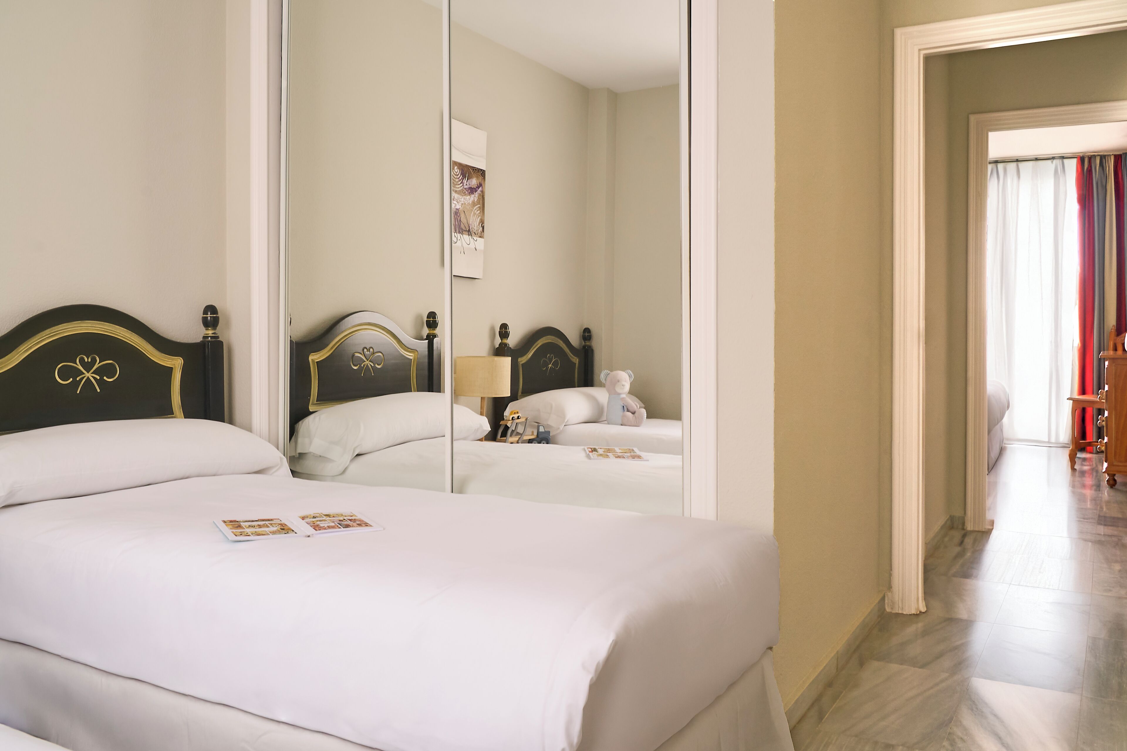 Habitación de hotel con una cama grande, un espejo y vistas al pasillo.