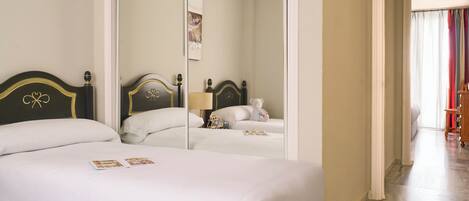 Habitación de hotel con una cama grande, un espejo y vistas al pasillo.