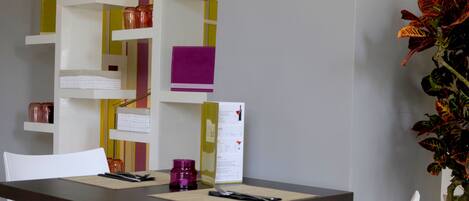 A dining area with a table, chairs, a menu, and a decorative plant.