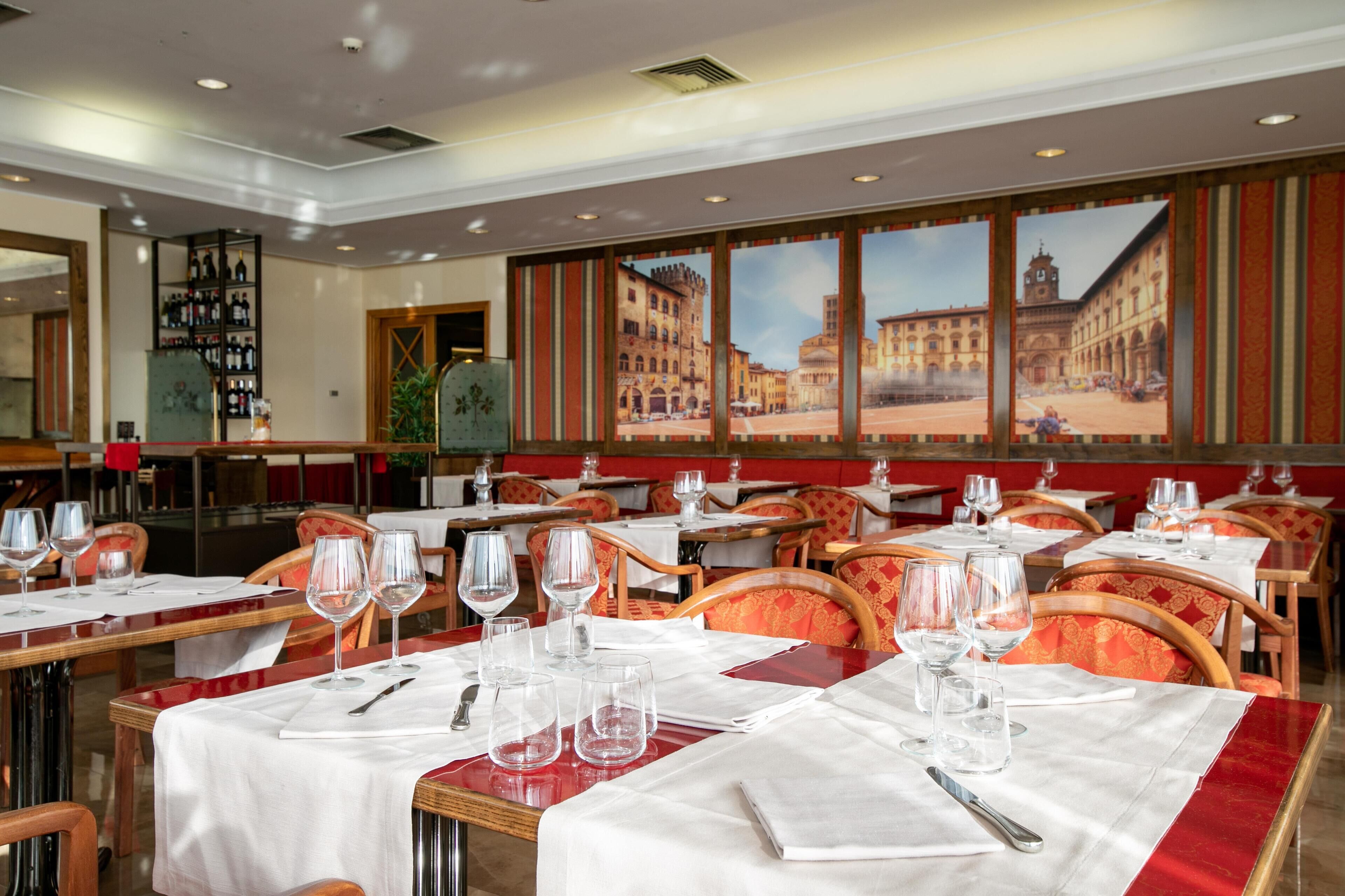 Ein Restaurant mit gedeckten Tischen, einem Weinregal und einem großen Fenster mit Blick auf die Stadt.
