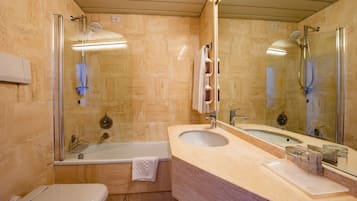 A modern bathroom with a glass-enclosed shower, a bathtub, a sink, and a toilet.