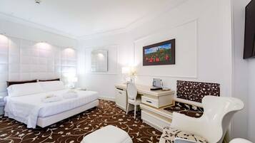 Een hotelkamer met een bed, bureau, stoel en een schilderij aan de muur.