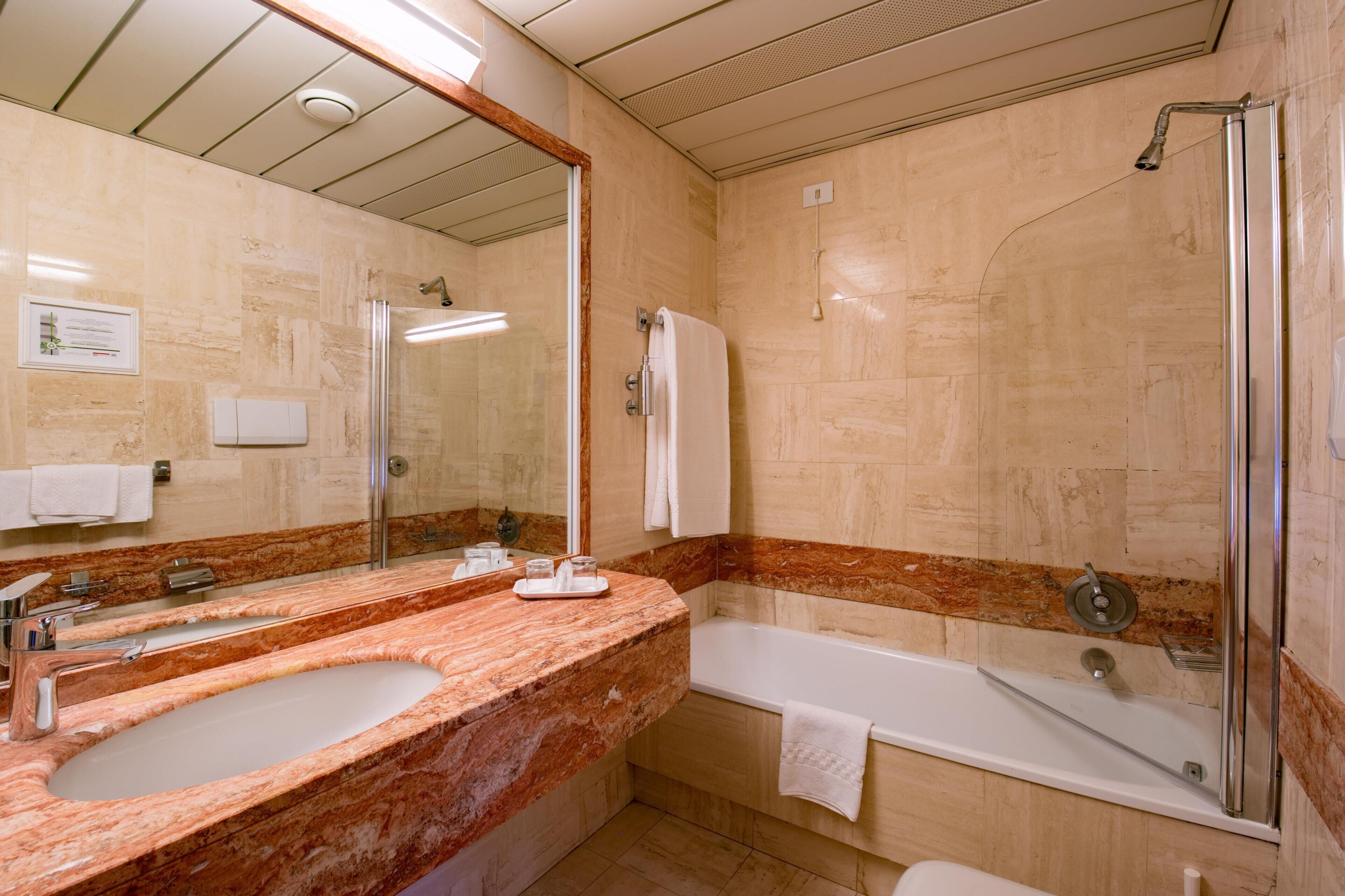 Un bagno con uno specchio grande, due lavandini, una vasca e una doccia.