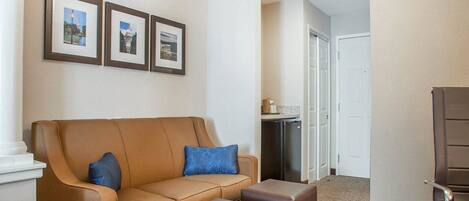 Un vestíbulo de hotel con un sofá de cuero marrón, dos otomanes a juego y tres cuadros en la pared.