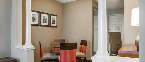 A hotel lobby with a reception desk, two chairs, a sofa, and framed pictures on the wall.