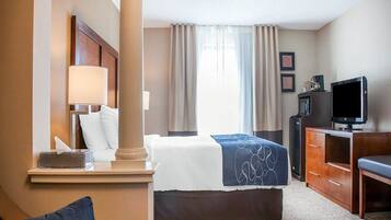 Una habitación de hotel con cama, escritorio con lámpara, televisión y cómoda.