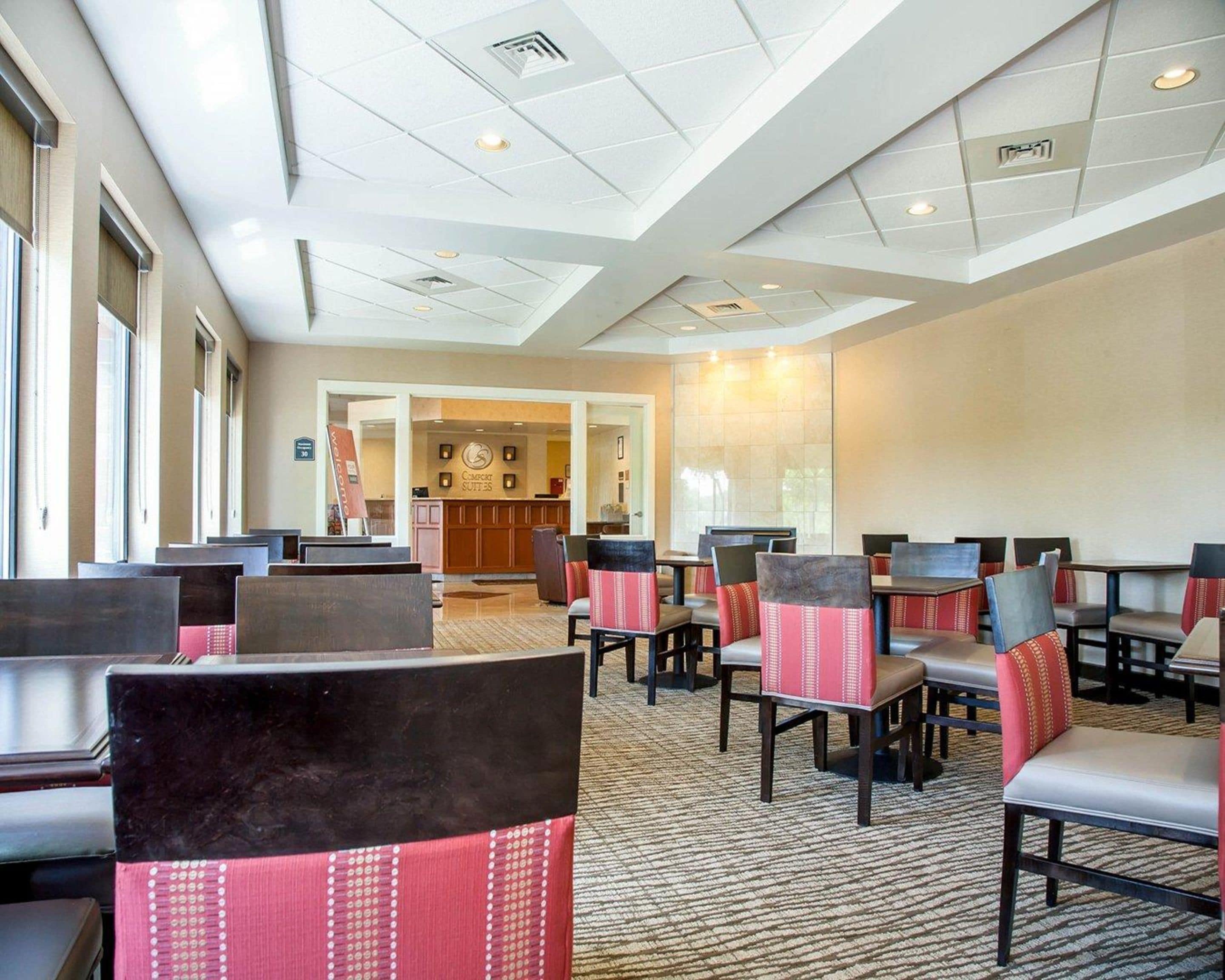 A hotel lobby with multiple seating areas, a reception desk, and a large window providing natural light.