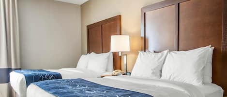 A hotel room with two beds, a nightstand with a lamp, and a window with curtains.