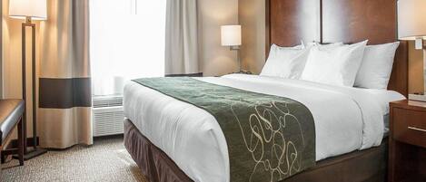 A hotel room with a large bed, two bedside lamps, a desk, and a chair.