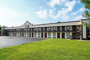 A Red Roof Inn with a two-story structure, a parking lot, and a grassy area in front.