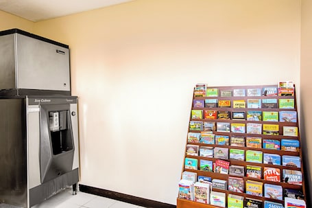 A kitchen area with a refrigerator, an ice dispenser, and a wall-mounted display of travel guides.