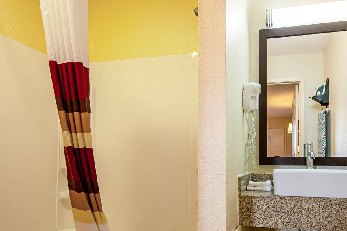 A bathroom with a white sink, a mirror, and a shower curtain.