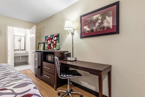 A hotel room with a bed, a desk, a chair, a microwave, a coffee maker, and a framed picture on the wall. - Red Roof Inn Scottsburg (Scottsburg)