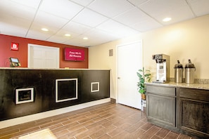 Un espace d’accueil avec un mur rouge, une porte blanche et un panneau indiquant que le Wi-Fi est disponible gratuitement dans toutes les chambres.