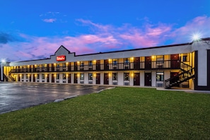 Un hôtel Red Roof Inn avec un bâtiment à deux étages, un espace de stationnement couvert et une pelouse bien entretenue.