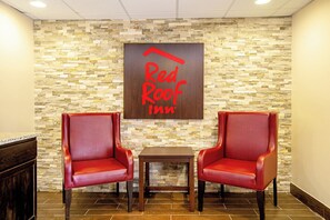 Een Red Roof Inn met twee rode leren fauteuils en een kleine tafel in de lobby.