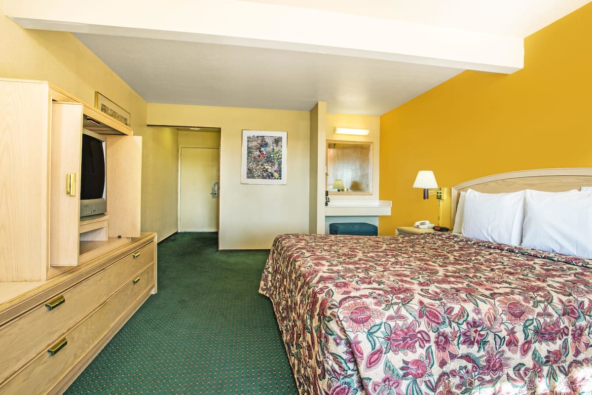 Une chambre d’hôtel comprenant un lit, une commode, un miroir et une porte donnant sur une autre pièce.