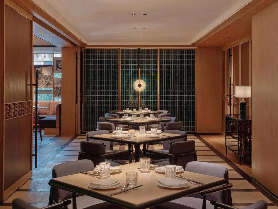 A hotel dining area with multiple tables, chairs, and a central decorative light fixture.