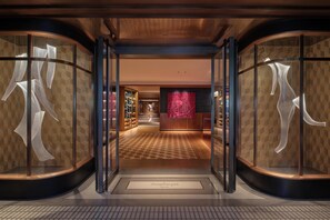 A hotel entrance with glass doors, a checkered floor, and a central wall with a pink abstract design. - Hyatt Centric Zhongshan Park Shanghai (Shanghai)