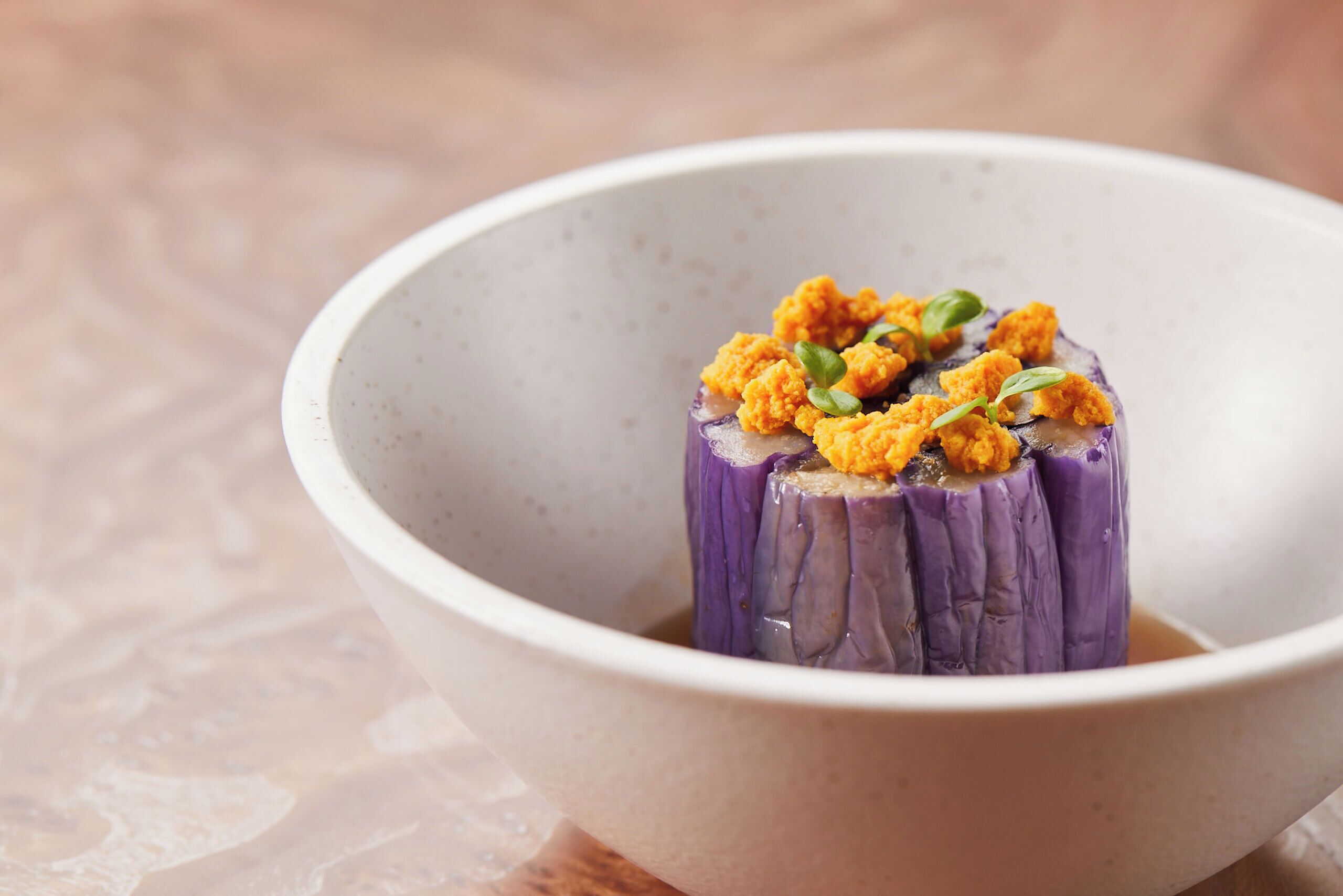 A bowl with a purple vegetable and some yellow topping.