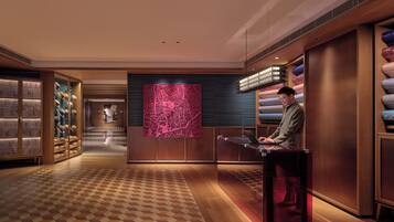 A modern hotel lobby with a check-in counter, a large map mural, and plush seating areas.