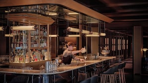 Zona de bar con un cantinero, taburetes y una amplia variedad de licores.