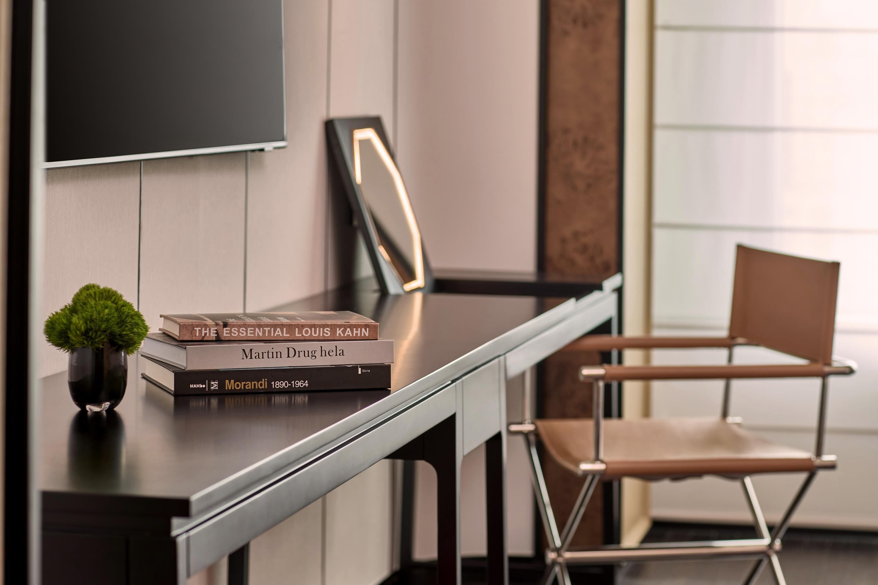 Una habitación moderna con escritorio, una silla, una planta en maceta y libros.