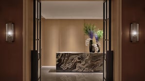 A reception area with a marble reception desk, a vase with flowers, and wall-mounted lighting.