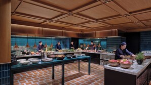 Una cocina moderna con chefs preparando comida, suelo de ladrillo y paneles de techo de madera.