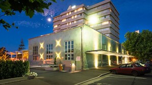 A multi-story hotel with a modern design, featuring a parking area and a covered entrance.