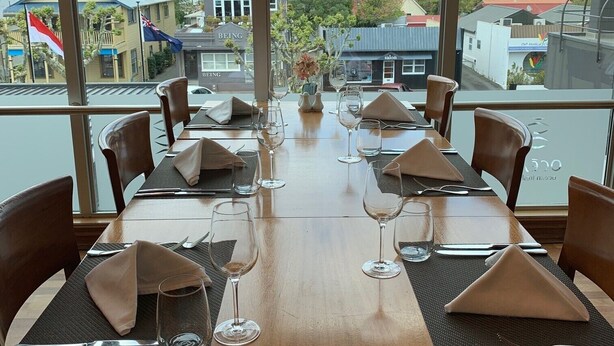 A dining table set with chairs, a view of a town and hills in the background.