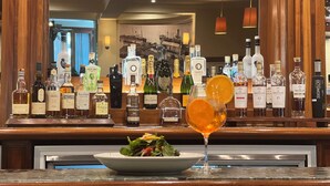 A bar area with various liquor bottles and a glass of orange juice on the counter.