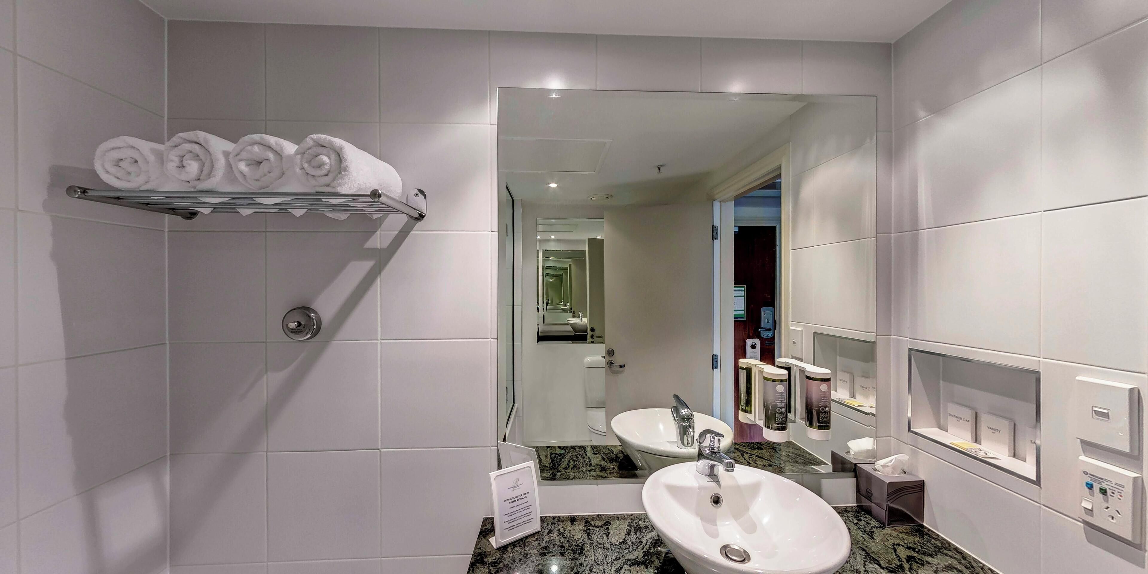 Un baño moderno con lavamanos, espejo, toallero y artículos de aseo.